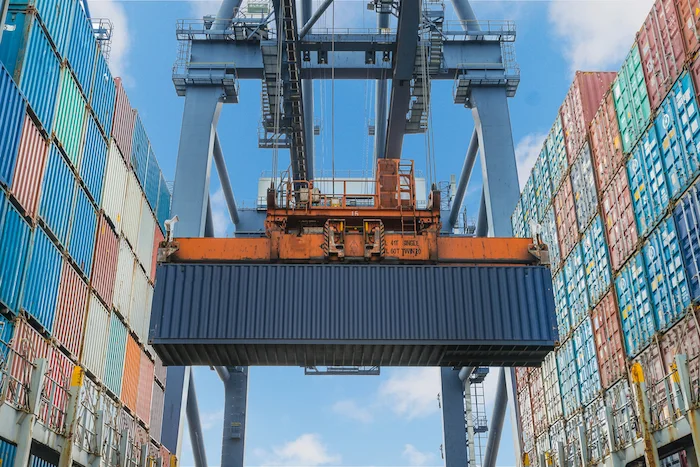 Shipping container being lifted by machinery